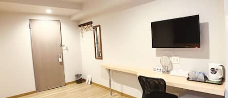 Un petit bureau comprenant un bureau, une chaise, un téléviseur et un réfrigérateur.