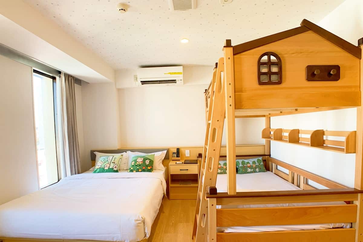 A bedroom with a bunk bed, a bedside table, a lamp, and a window with curtains.
