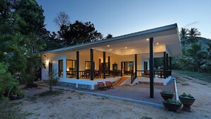 A modern house with a covered porch, outdoor seating, and a gravel driveway. - 155 SalaCoco (Bang Saphan)