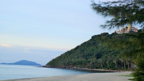 A beach with a forested hill and a building on top. - 155 SalaCoco (Bang Saphan)