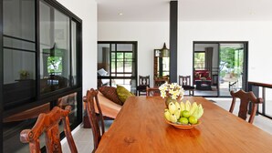 A spacious dining area with a wooden table, chairs, and a bowl of fruit. - 155 SalaCoco (Bang Saphan)