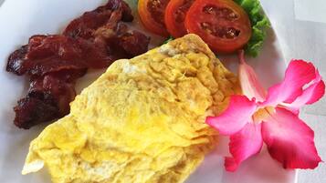Un plato con tocino, una tortilla y tomates en rodajas sobre un plato blanco.
