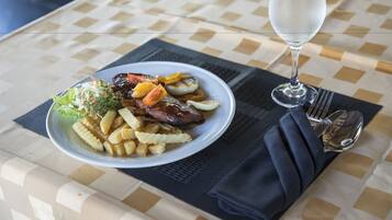 Un plato de comida con un vaso de agua sobre una mesa con mantel a cuadros.