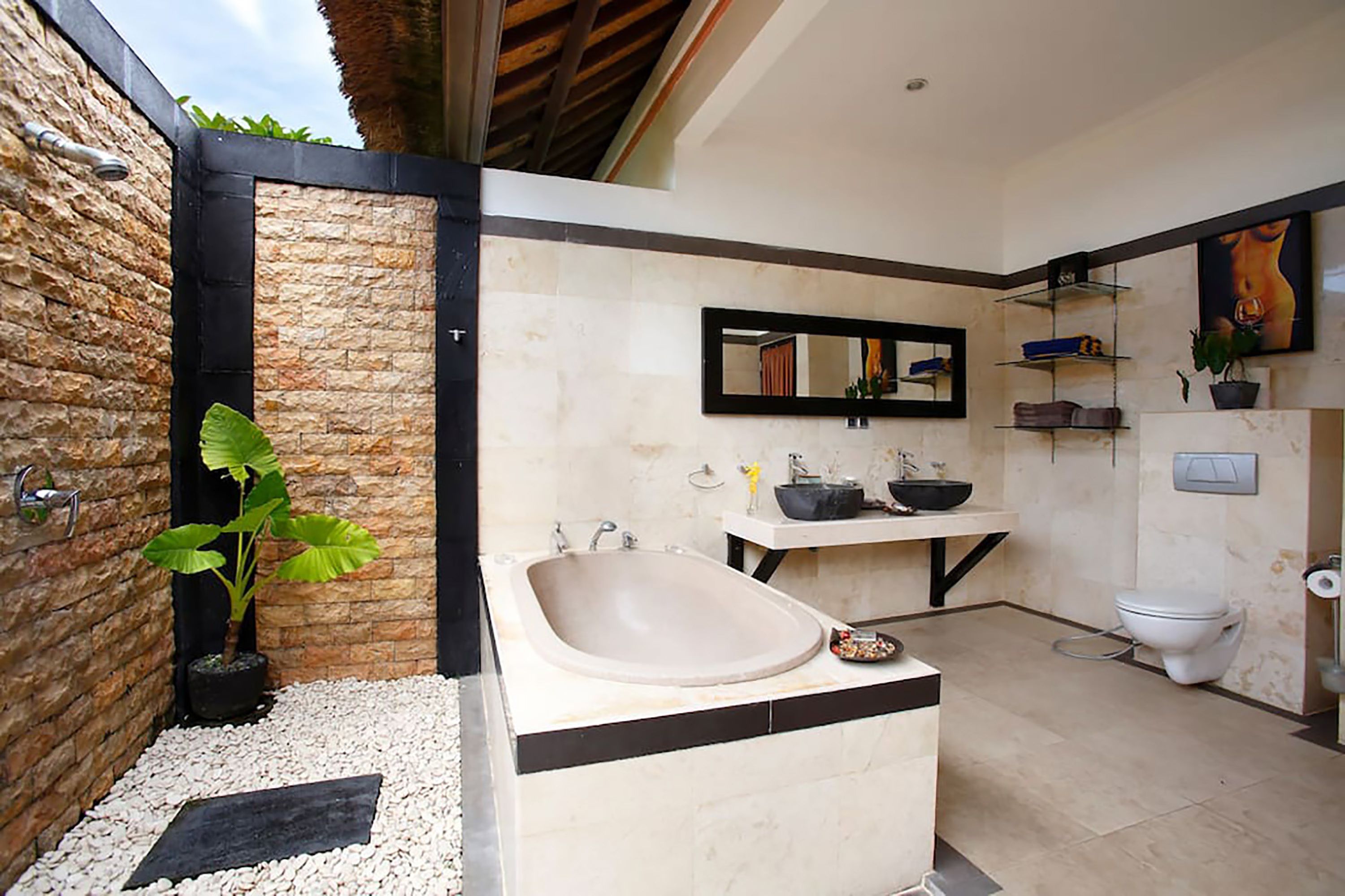 A modern bathroom with a freestanding bathtub, a large mirror, and a sink with a black countertop.