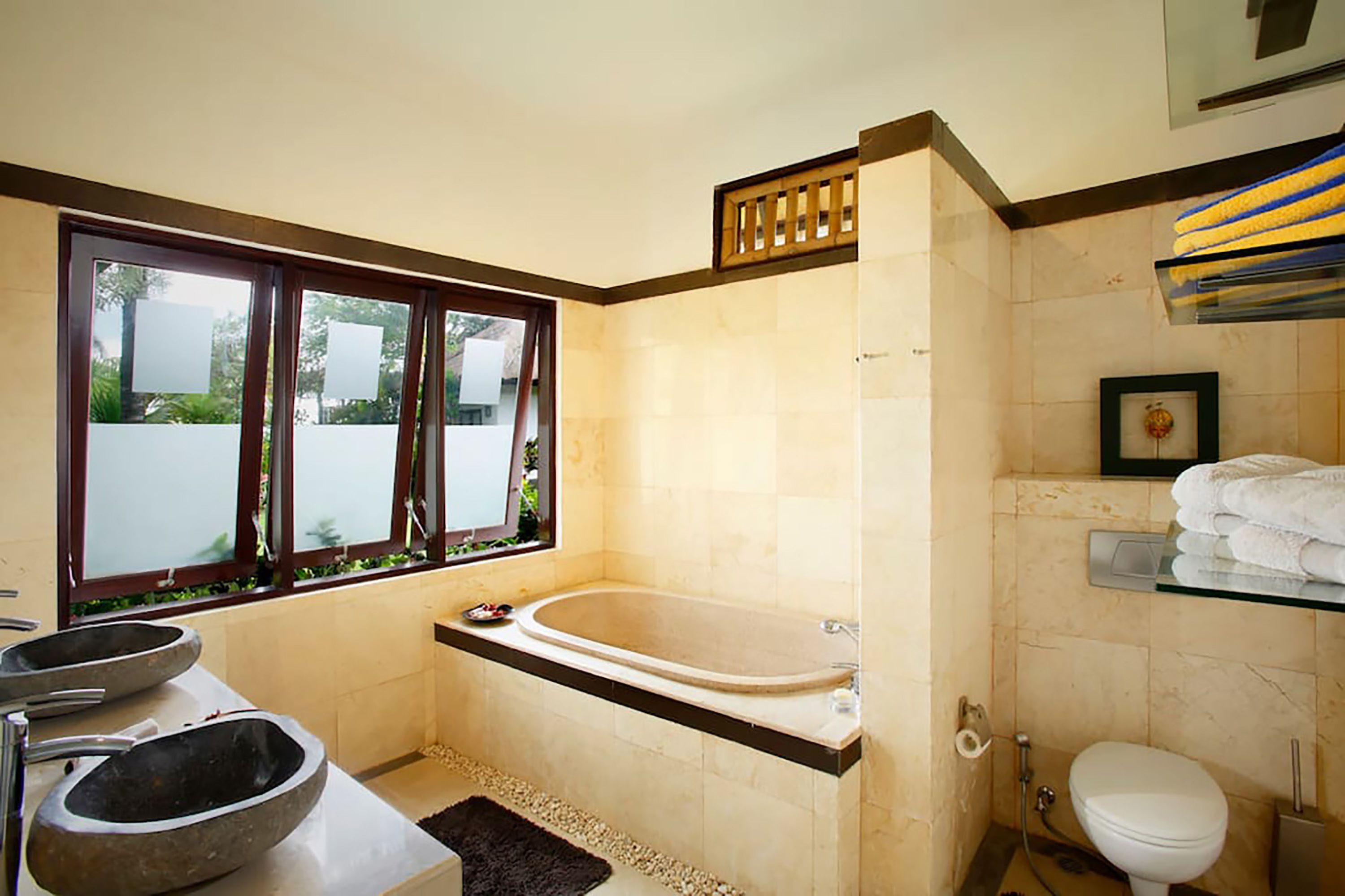 Un baño con bañera, inodoro y ventana con vistas al verdor.