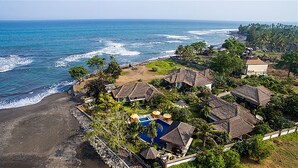 A coastal resort with thatched-roof buildings, a swimming pool, and a beach. - Villa L'Orange Bali (Gianyar)