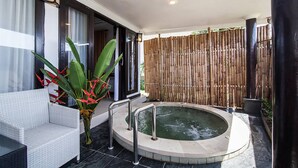 A spa area with a hot tub, a white wicker sofa, and a bamboo fence. - Villa L'Orange Bali (Gianyar)
