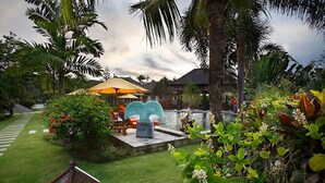 A tropical garden with a pool, lounge chairs, and a gazebo. - Villa L'Orange Bali (Gianyar)