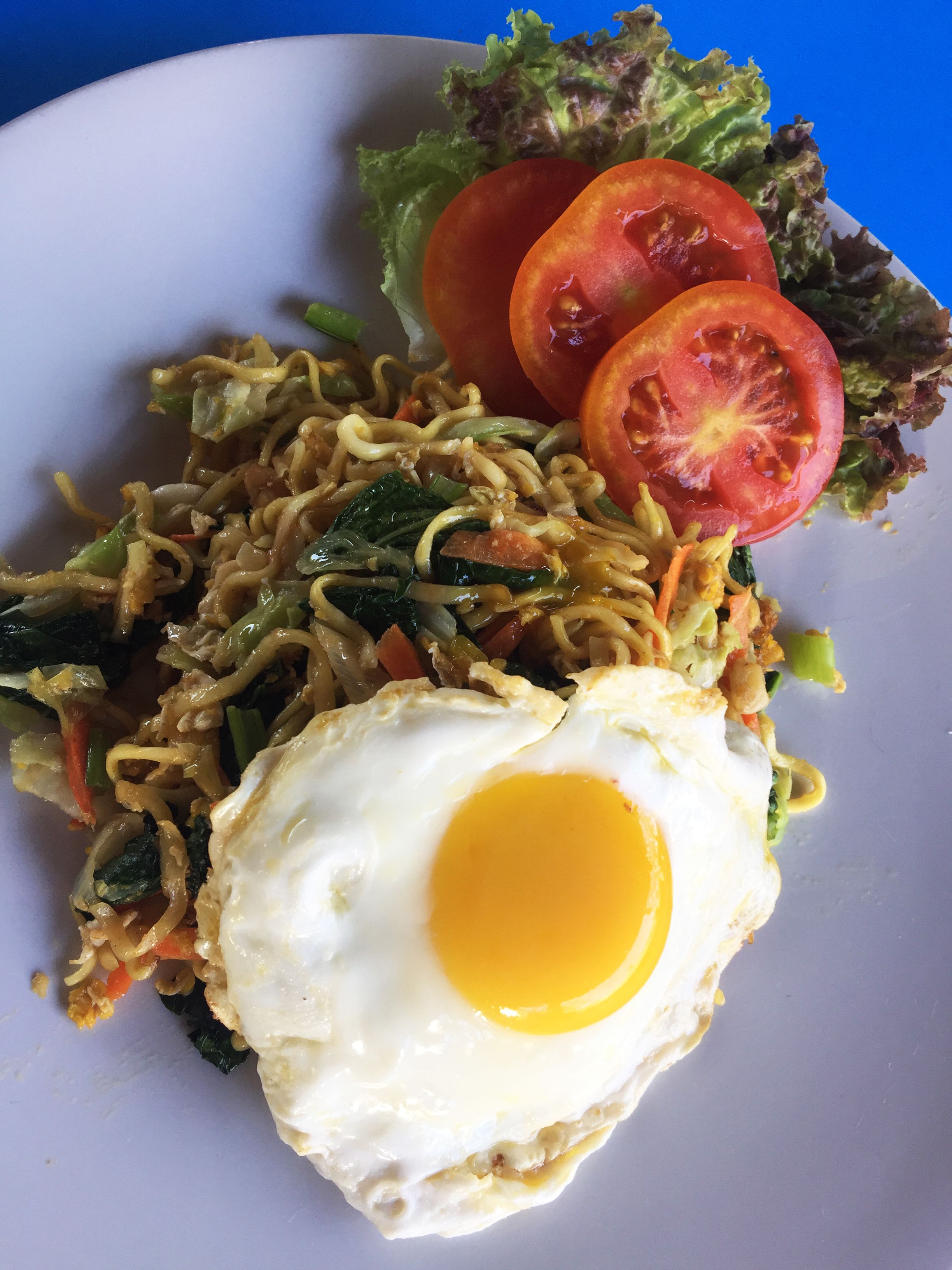 A plate of stir-fried noodles with vegetables and a fried egg.