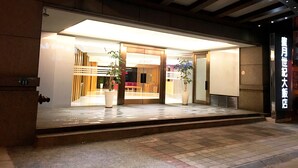 A hotel entrance with a modern design, featuring a glass facade, a wooden reception desk, and potted plants. - Century Hotel Taoyuan (Taoyuan City)