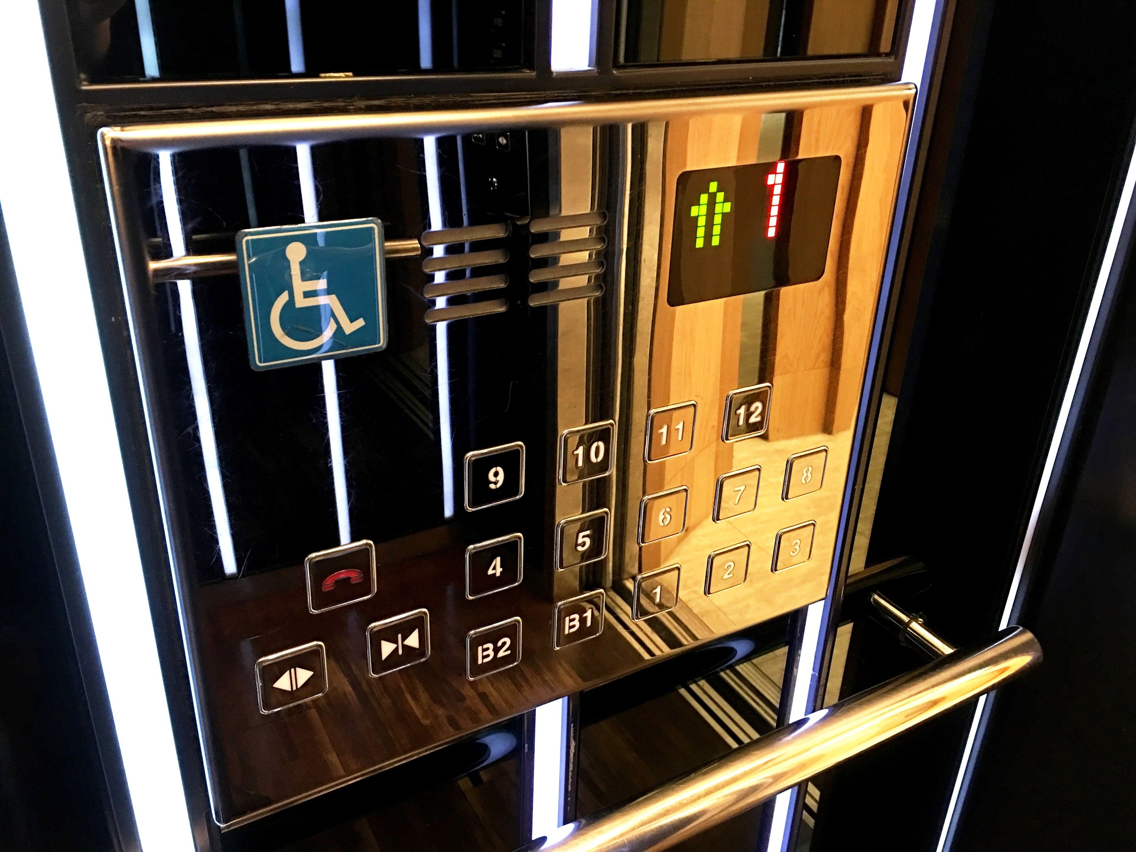 An elevator control panel with a wheelchair accessibility sign, a numeric keypad, and directional arrows.