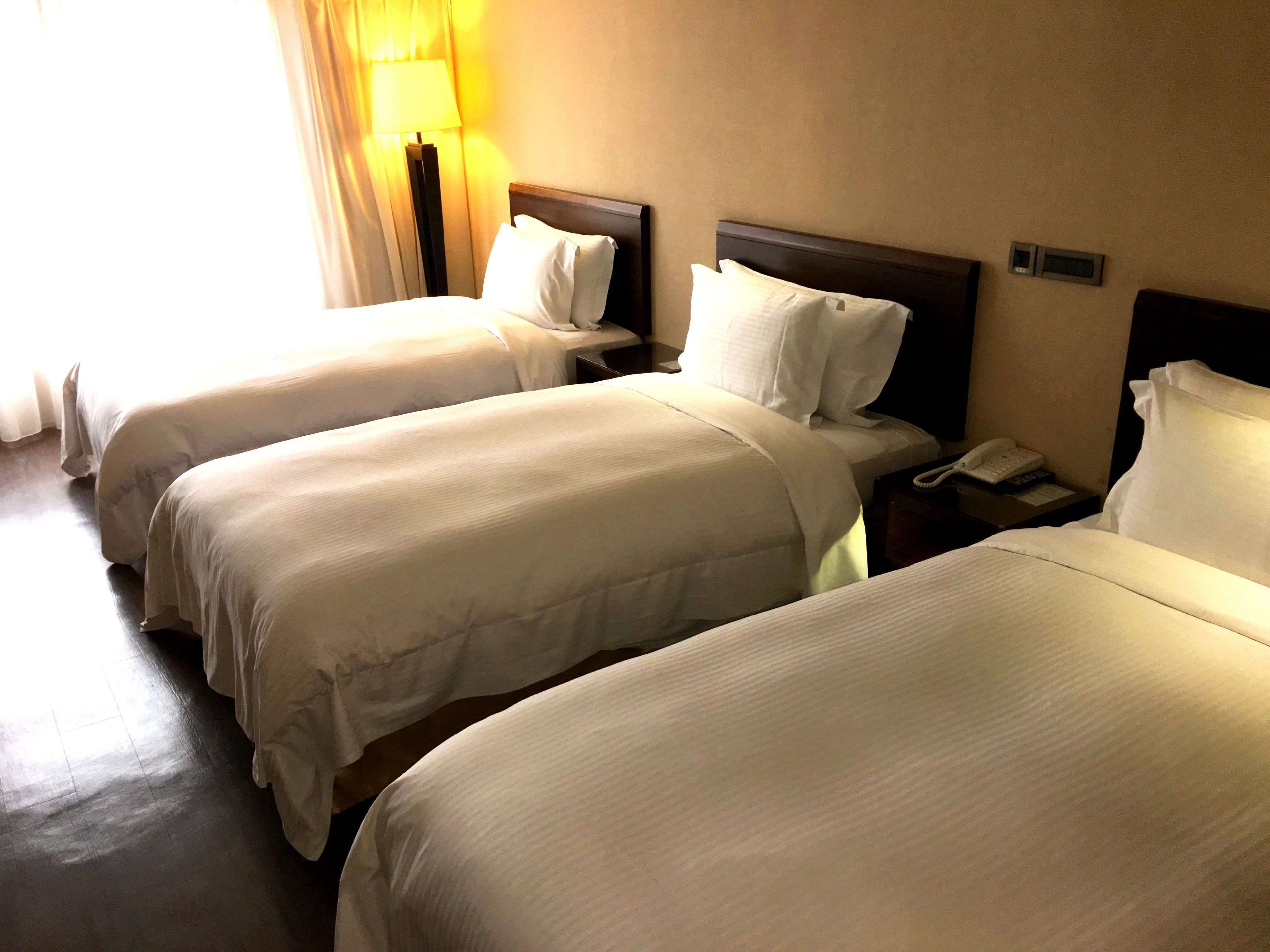 A hotel room with two single beds, a bedside table with a lamp, and a telephone.