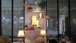 Um hall de hotel com design moderno, apresentando um relógio grande, plantas em vasos e uma citação sobre liberdade na parede.