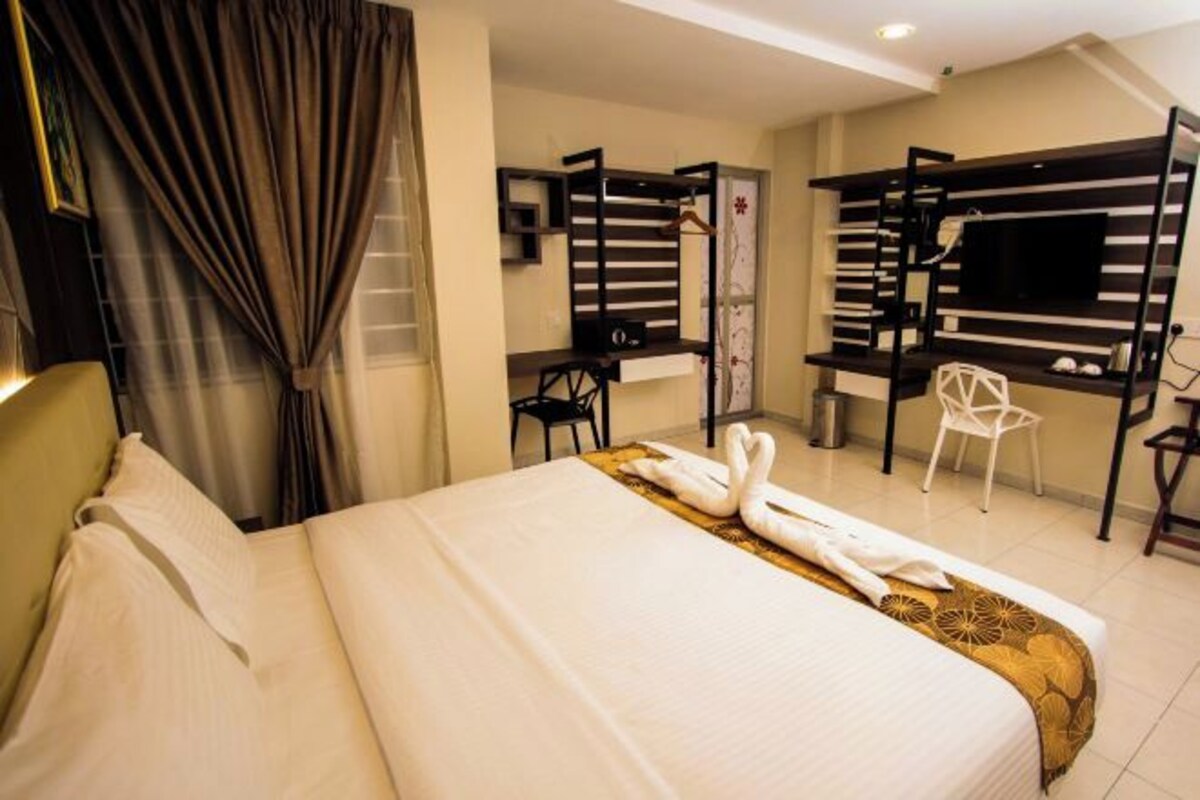 A hotel room with a large bed, a desk, a TV, and a chair.
