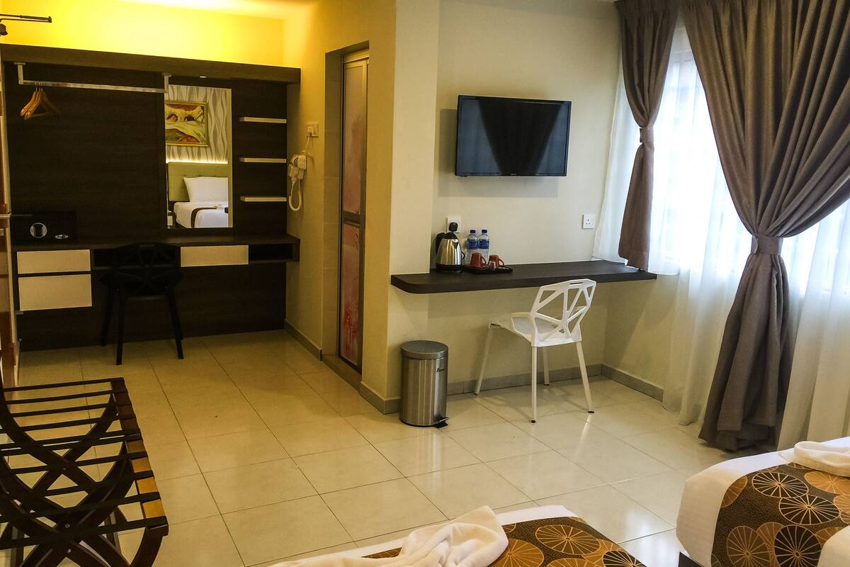 Una habitación de hotel con cama, escritorio, silla, televisor y armario.