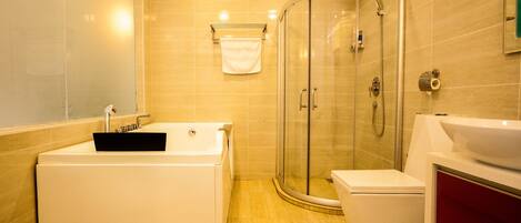 Un baño moderno con ducha envuelta en vidrio, una bañera independiente y un inodoro.