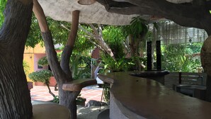 Un área de estar al aire libre con bancos de piedra y una fuente de agua, rodeada de árboles y plantas.