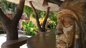 Una escultura con base curva, rodeada de árboles y un banco.