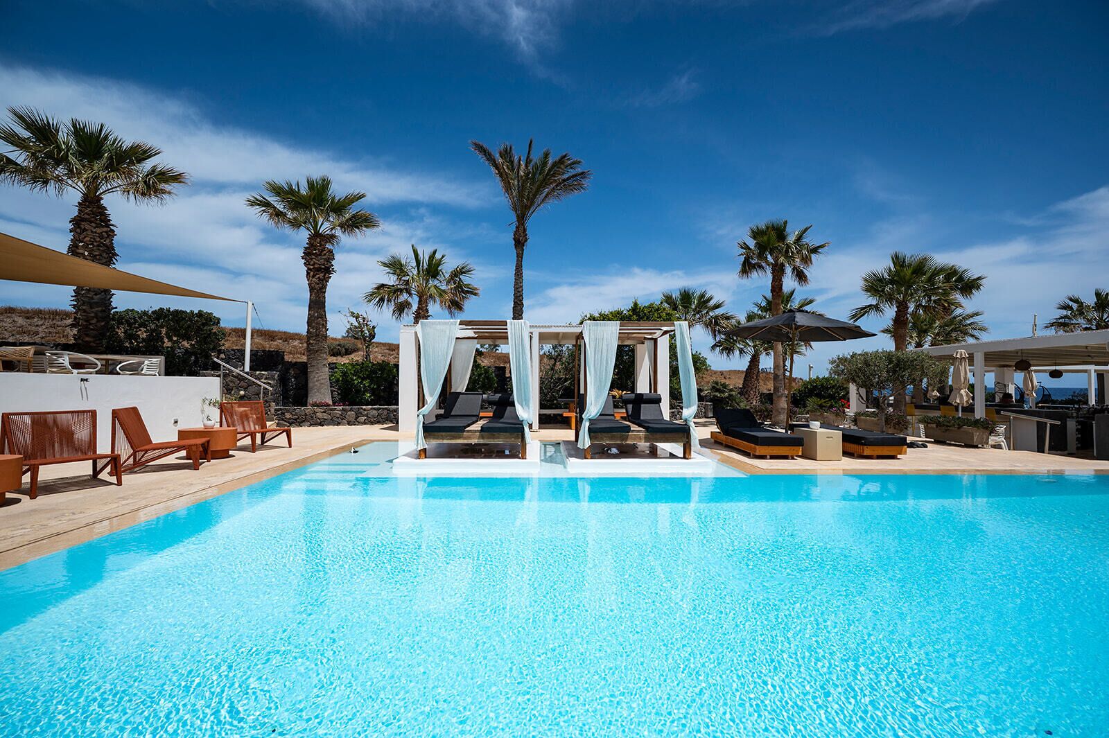 A clear blue pool with lounge chairs and a canopy structure.