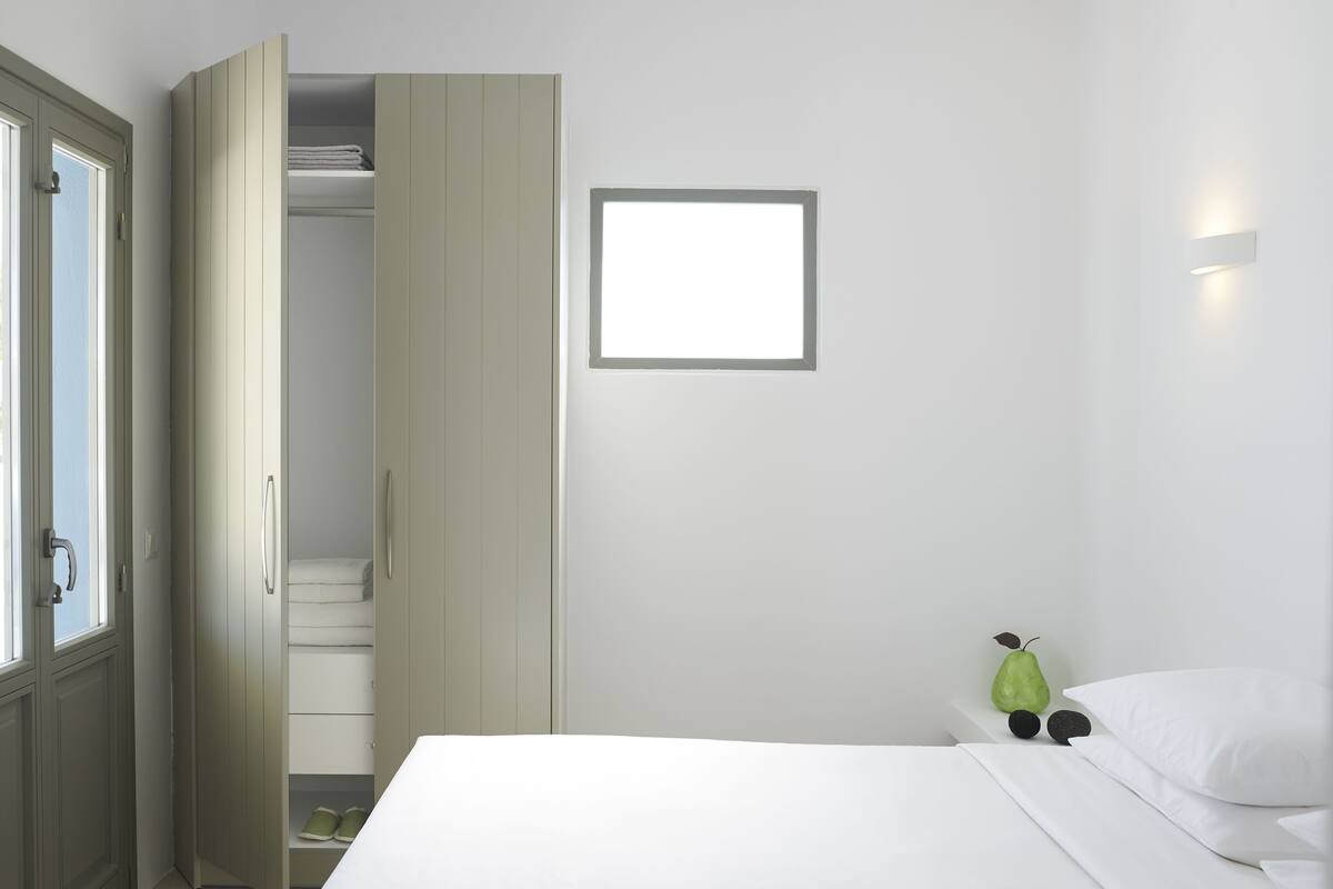 Une chambre à coucher comprenant un lit, une armoire, une porte et un luminaire fixé au mur.