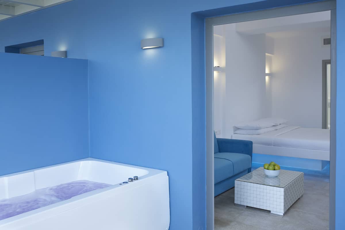 Une salle de bain moderne avec une baignoire, un mur bleu et une petite table de chevet sur laquelle se trouve un bol de fruits.