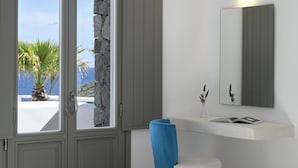 Un baño moderno con pared de piedra, una silla azul, un lavamanos blanco y un espejo.