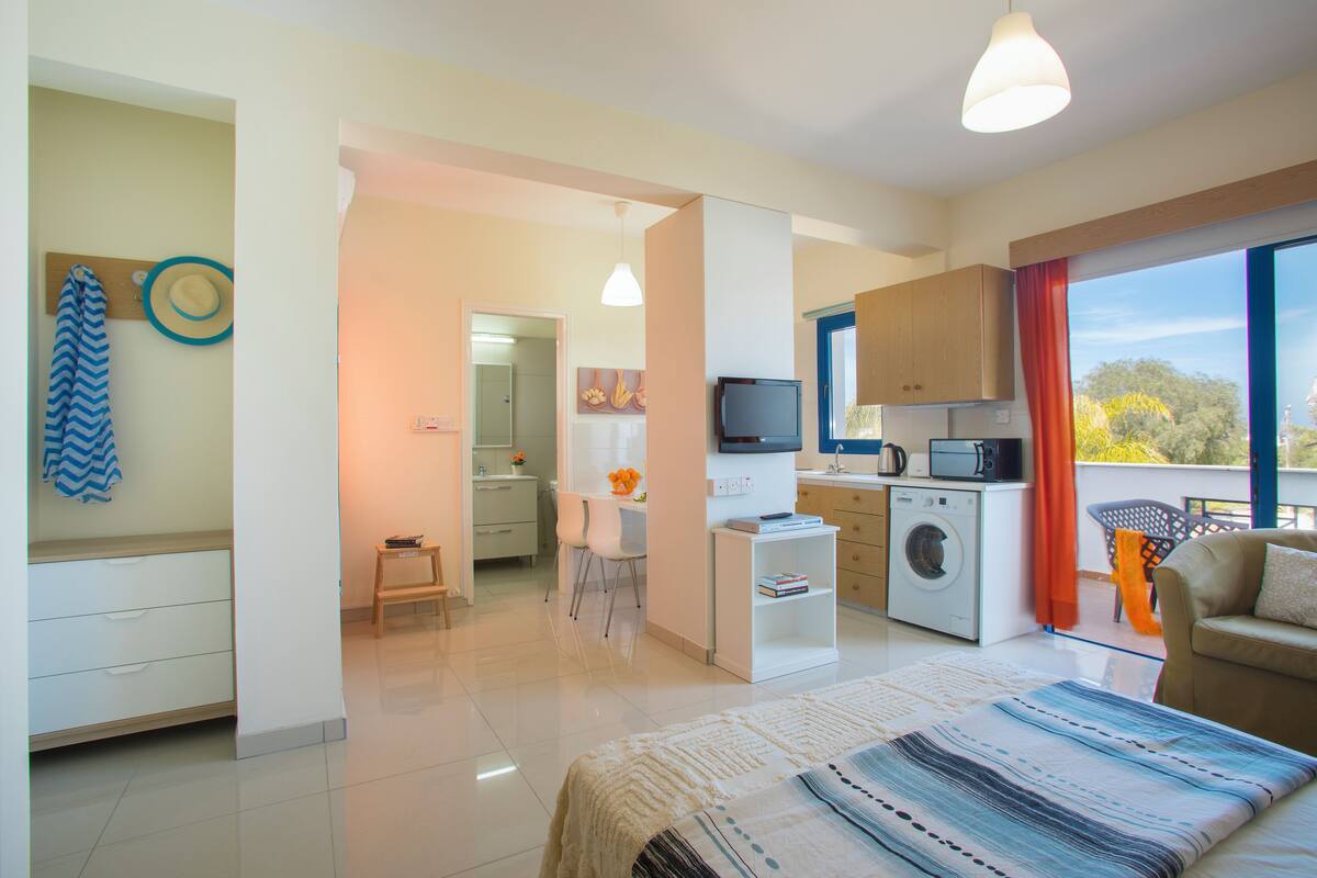 A modern apartment with a bedroom, living area, kitchen, and balcony.