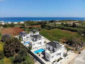 Un quartier résidentiel moderne avec des maisons blanches, une piscine et une vue sur la mer.