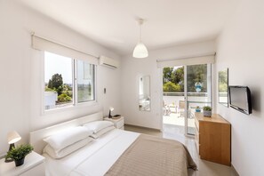 Une chambre à coucher moderne, avec un lit, une table de chevet, une lampe et une vue sur l’extérieur grâce à une porte-fenêtre coulissante.