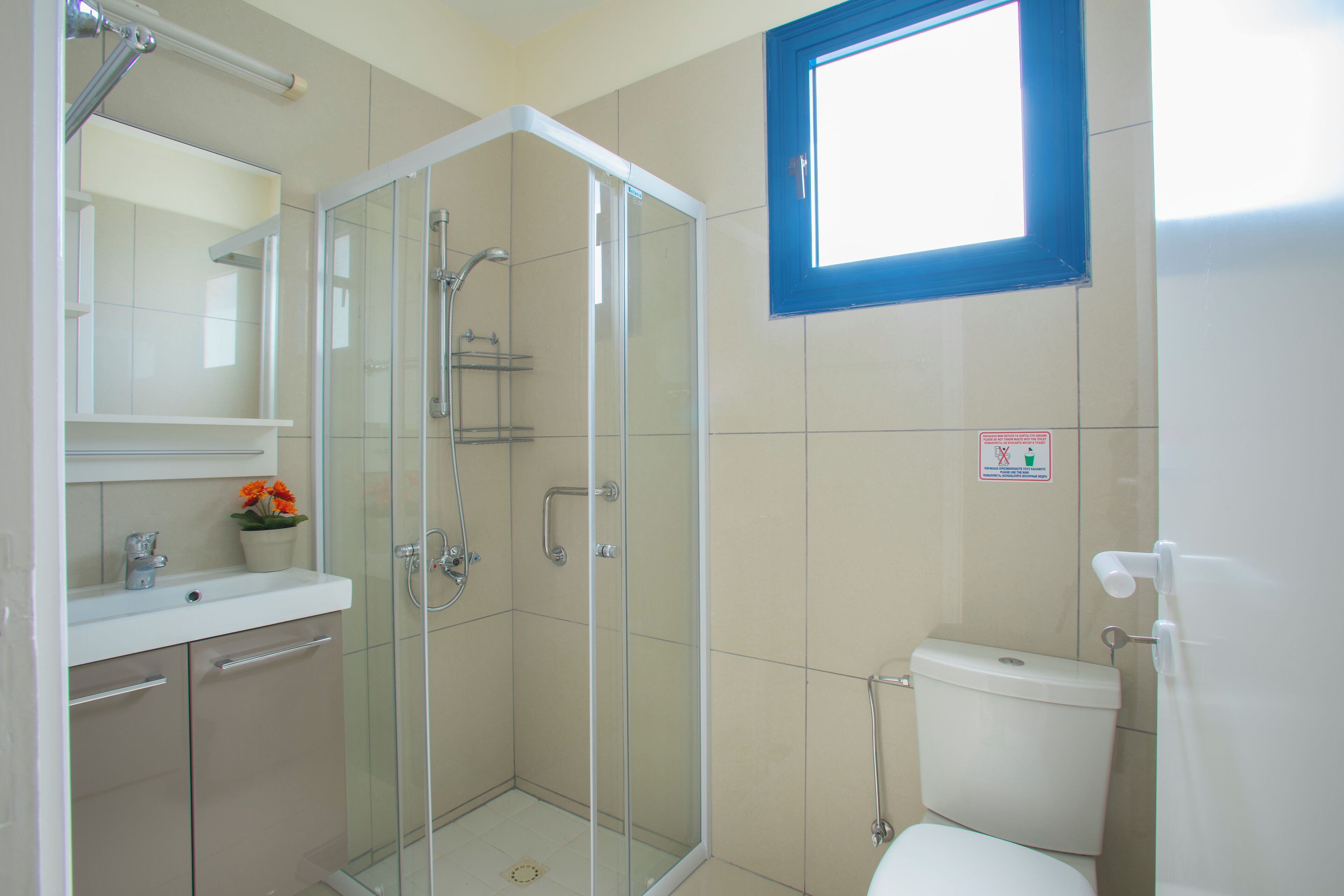 A modern bathroom with a glass-enclosed shower, a white sink, and a toilet.
