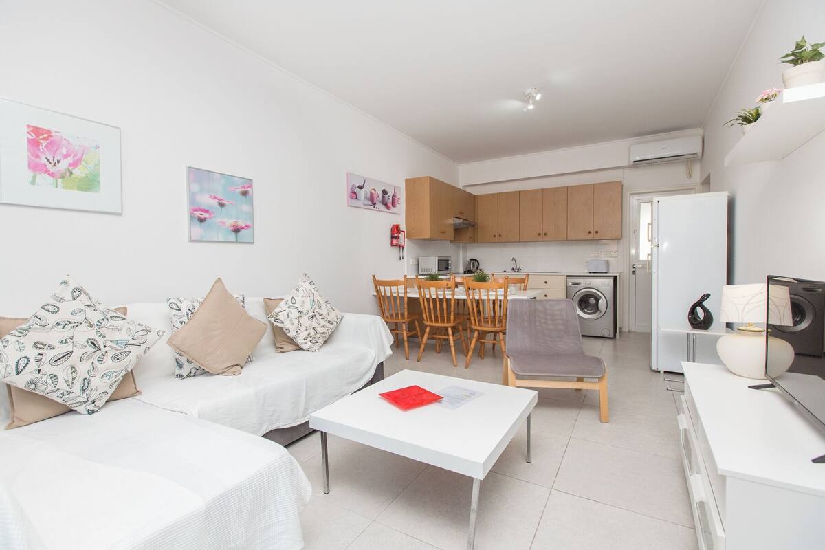 A modern apartment with a living room, dining area, kitchen, and a small laundry area.