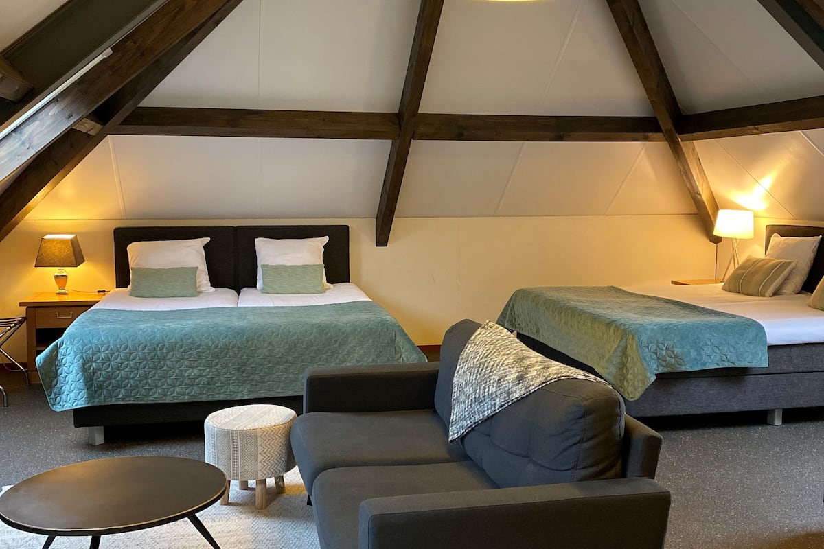 Une chambre confortable située sous les toits, avec deux lits, un canapé et une petite table.