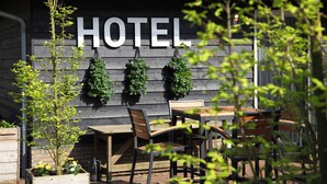A wooden building with a sign that reads "HOTEL" above a table and chairs set outside. - Hotel Hof van 's Gravenmoer (Gravenmoer)