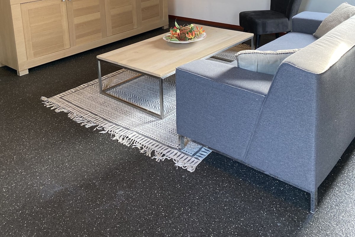 Un salon moderne avec un téléviseur à écran plat, un meuble en bois, un canapé gris et un tapis à motifs.