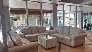 A spacious lobby with leather sofas and a marble coffee table, large windows offering views of parked cars and palm trees outside. - NEO Hatyai Hotel (Hat Yai)