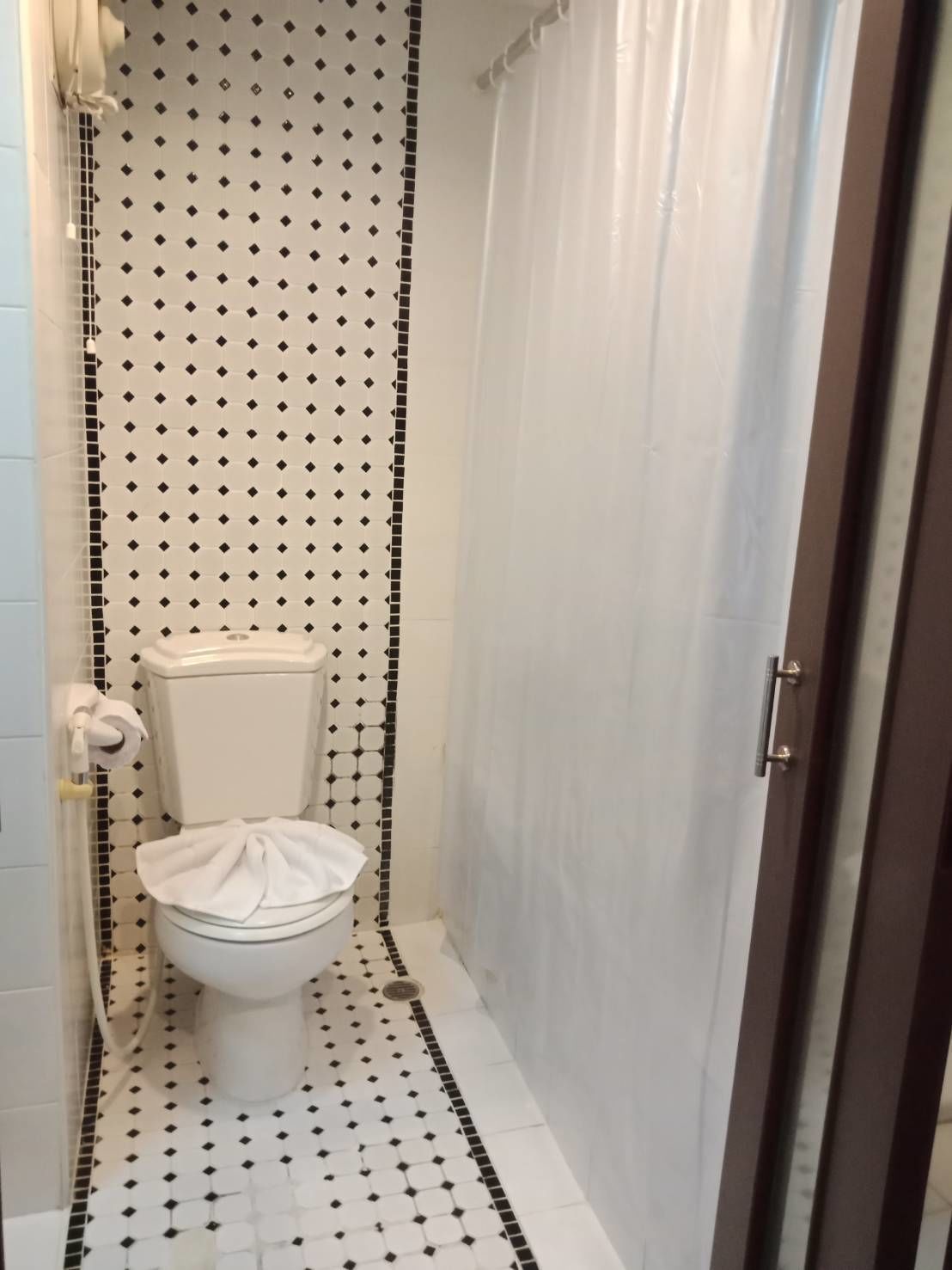 A bathroom with a toilet, a shower curtain, and a tiled floor.