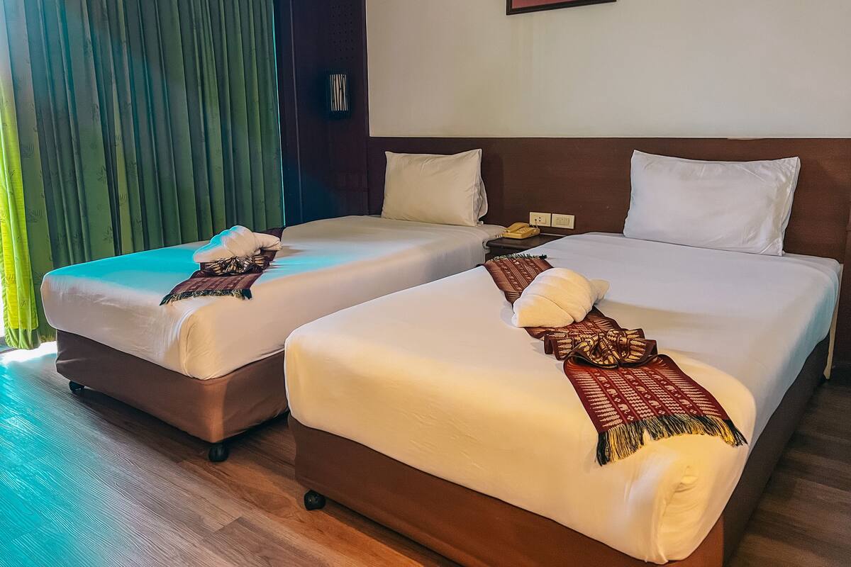 A hotel room with two beds, a telephone, and a wall-mounted light fixture.