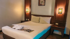A hotel room with a large bed, wooden headboard, two bedside tables, a telephone, and wall-mounted lights. - NEO Hatyai Hotel (Hat Yai)