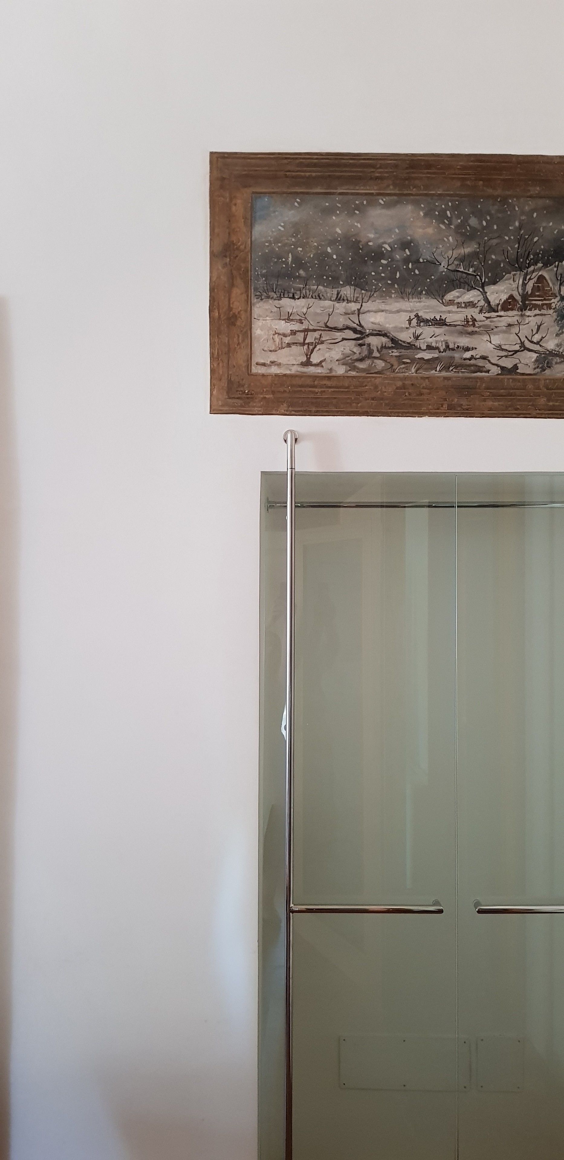 A modern kitchen with a glass-front refrigerator and a framed painting above it.