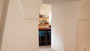 A breakfast table with a variety of food items, including pastries, fruits, and meats, set in a bright room with a view of a bar area in the background. - Dimora Intini (Noci)