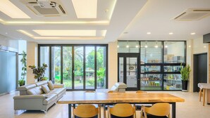 Un interior moderno con comedor, sofá y cocina visibles a través de puertas de vidrio.