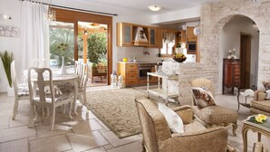 A spacious living area with a dining set, a sofa, and a kitchen in the background. - Pandora Villas (Hersonissos)