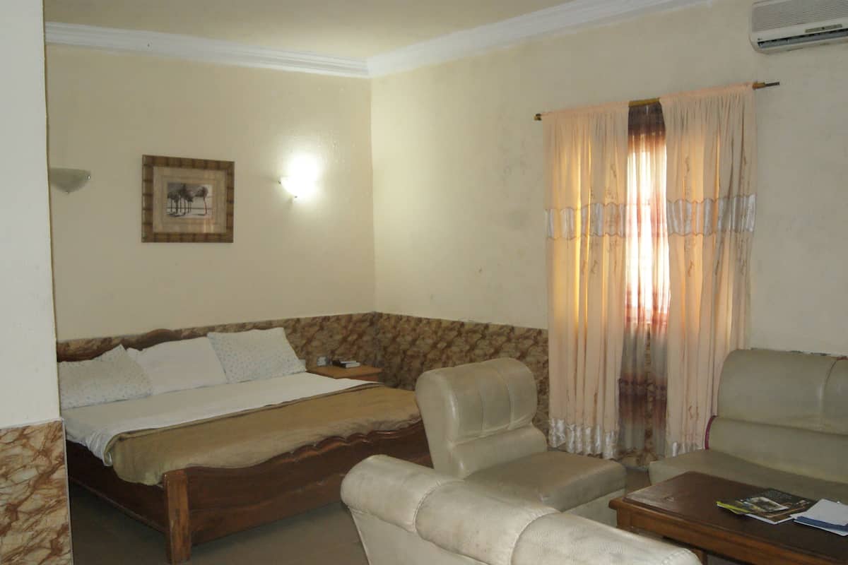 Une chambre d’hôtel avec un lit, deux chaises, une petite table et un rideau.
