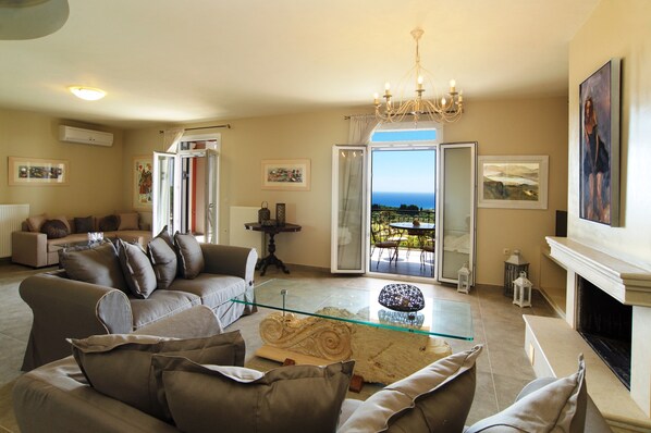 A living room with a glass coffee table, a fireplace, and a view of the outdoors.