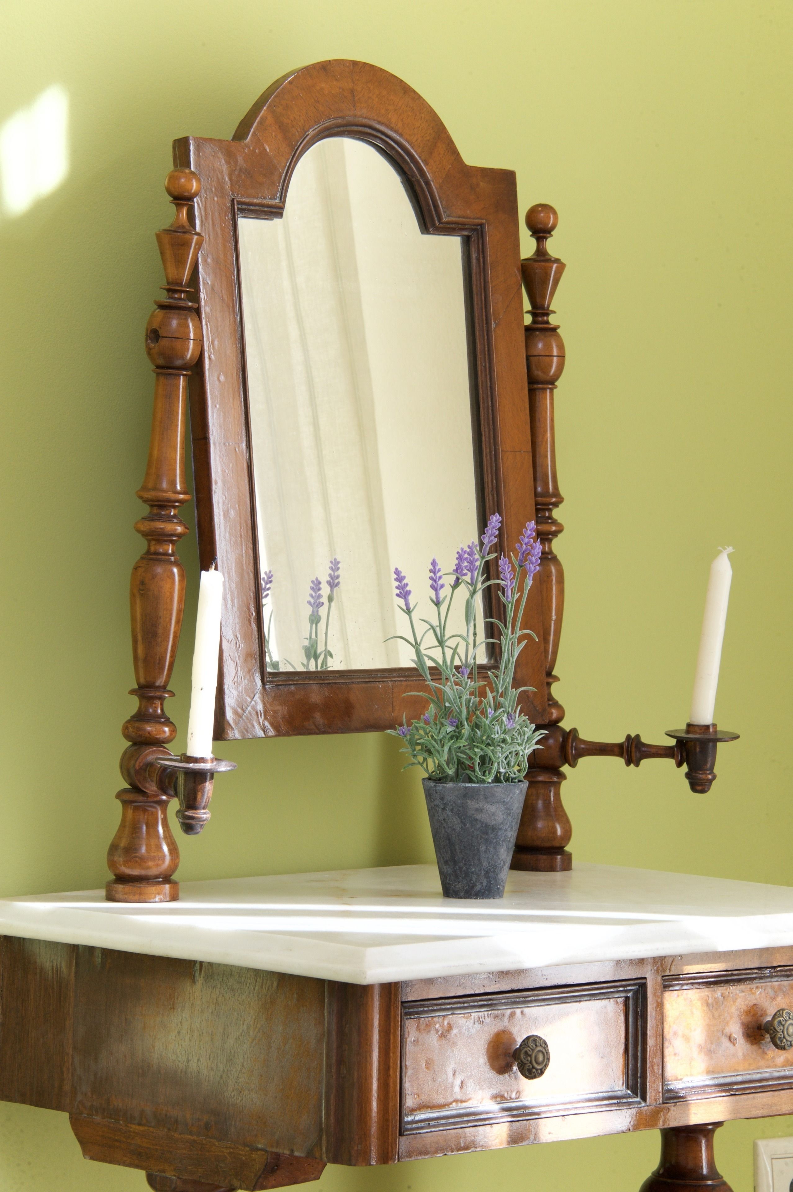A wooden dresser with a mirror, a candle holder, and a potted lavender plant.