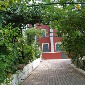 A paved pathway leading to a building with a red facade and white trim.
