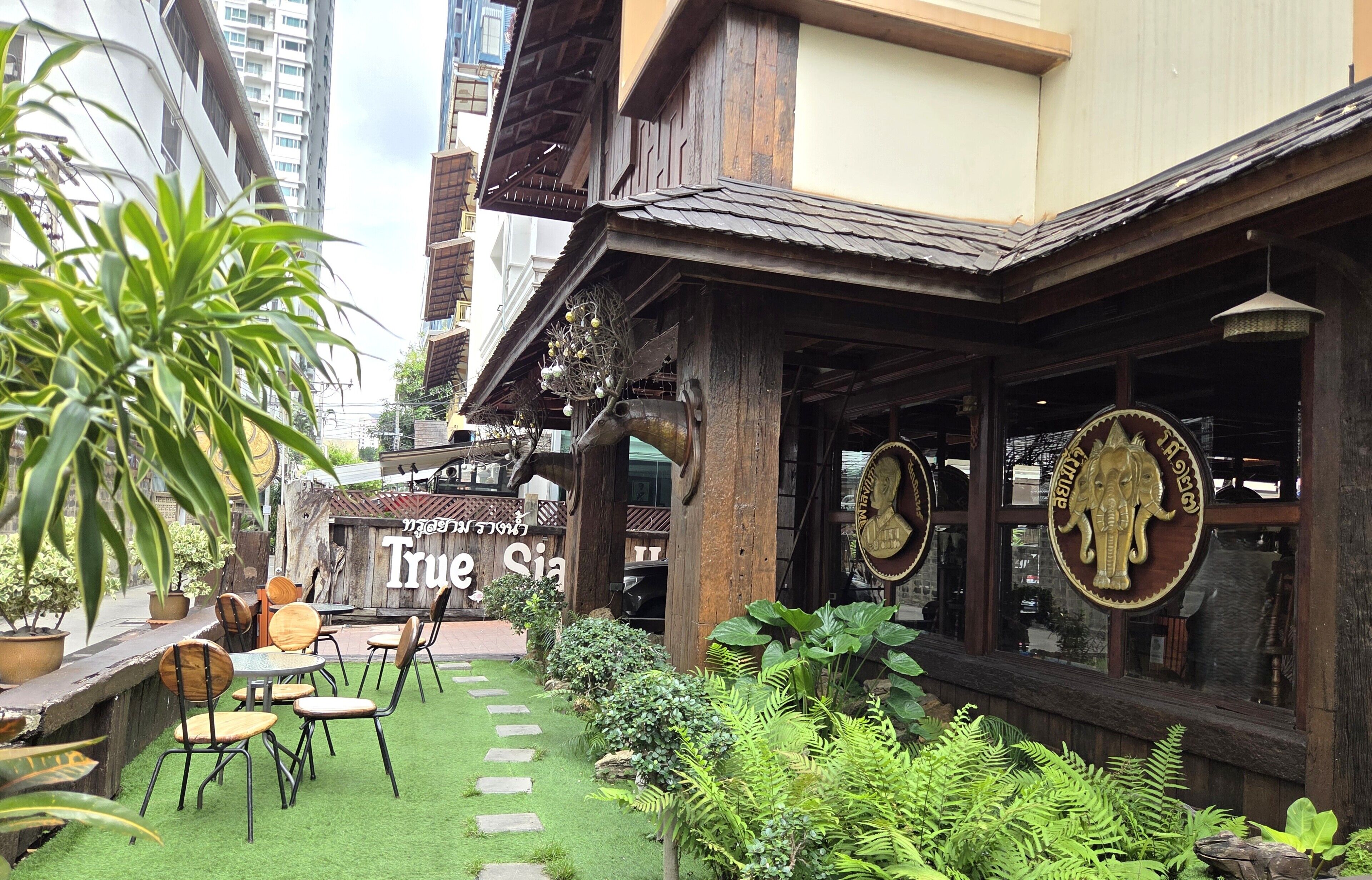 A restaurant with outdoor seating, a sign reading 'True Siam,' and a Buddha statue.