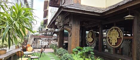 A restaurant with outdoor seating, a sign reading 'True Siam,' and a Buddha statue.