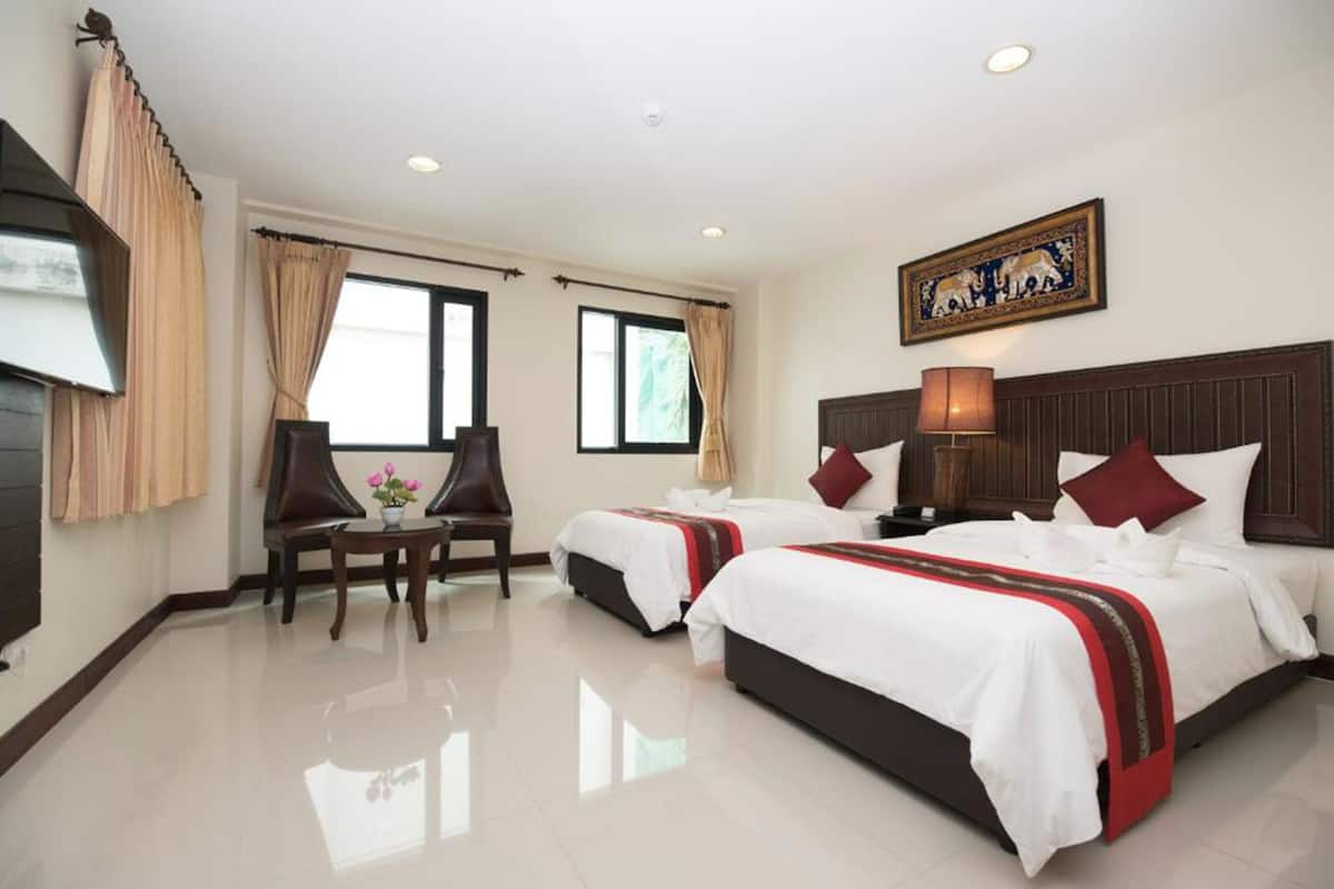 A hotel room with two beds, a TV, a desk with a chair, and a window with curtains.