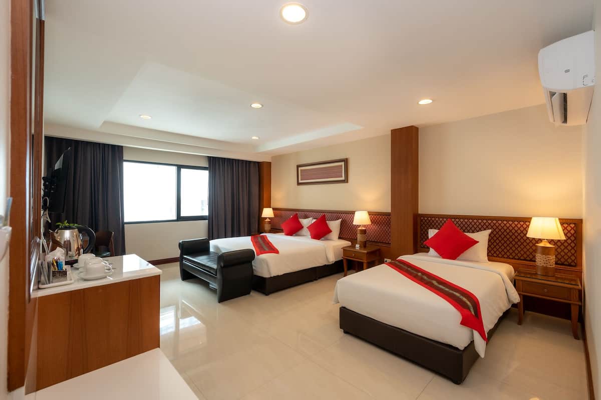 A hotel room with two beds, a desk, a chair, and a window with curtains.